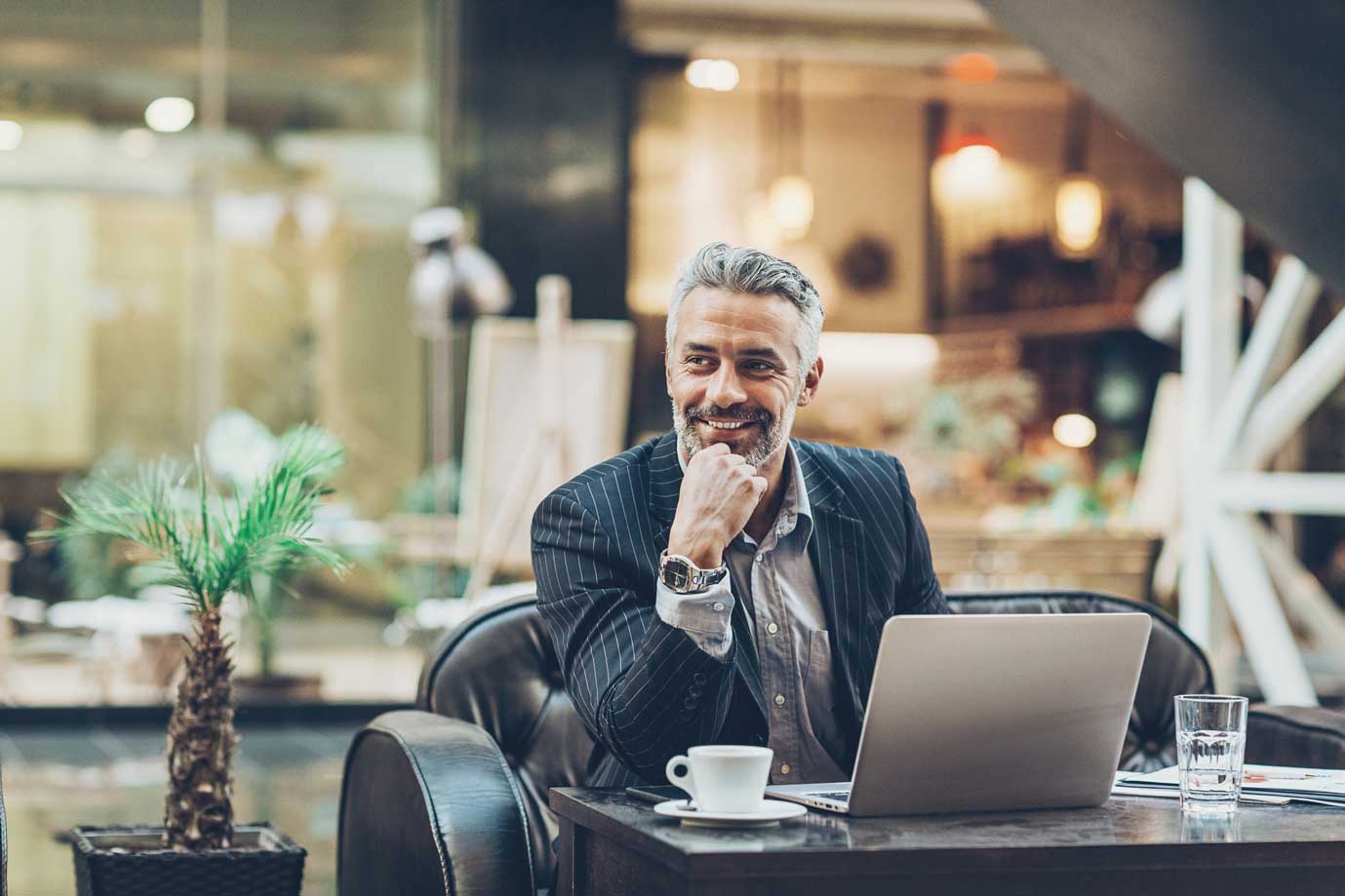 Man in suit with coffee and laptop